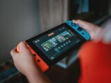 person holding black and orange nintendo switch