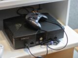 Here's a caption: an original xbox console with a controller.