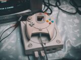 Close-up of a Sega Dreamcast console with controller and CRT monitor in a retro gaming setup.