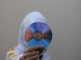 a person in a white hoodie holding a cd
