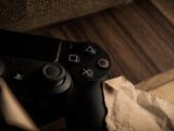 A close-up of a PlayStation gaming controller resting on a wooden surface with a rustic feel.