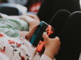 person holding blue and orange Joy Con controller
