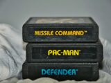 Close-up of vintage Atari game cartridges for Missile Command, Pac-Man, and Defender.
