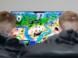 two boys are playing a video game on the television