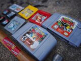 a group of nintendo games sitting next to a baseball bat