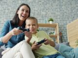 Mother and son playing video games together on couch