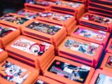 Close-up of stacked retro video game cartridges in orange cases, showcasing popular titles.