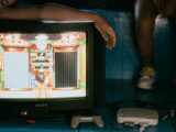 Crop unrecognizable female on modern monitor with video game on screen near ethnic partner