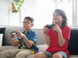 Two kids playing video games on a cozy couch indoors, showcasing fun and technology.