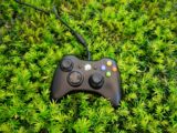 a video game controller laying on top of a lush green field