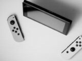Black and white minimalist flat lay of Nintendo Switch console with game controllers on a white surface.