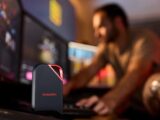 Portable ssd on desk with man working at computer.