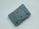Close-up of a vintage Sony PlayStation console on a white background, highlighting retro gaming vibes.