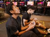Two teenagers deeply engaged in a video gaming session at an indoor arcade.