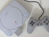 Top view of a classic Sony PlayStation console with a controller on a white surface.