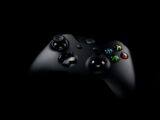 Close-up of a black wireless gaming controller on a dark background, highlighting its buttons.