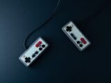 Top view of two retro gaming controllers on a minimalist dark background.
