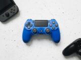 A top view of various colorful gaming controllers on a white surface.
