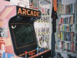 An arcade machine in front of a bookshelf