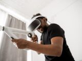 Smiling man immerses in virtual reality gaming experience indoors with futuristic VR headset.