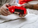 Close-up of hands holding a red game controller, perfect for gaming and technology themes.